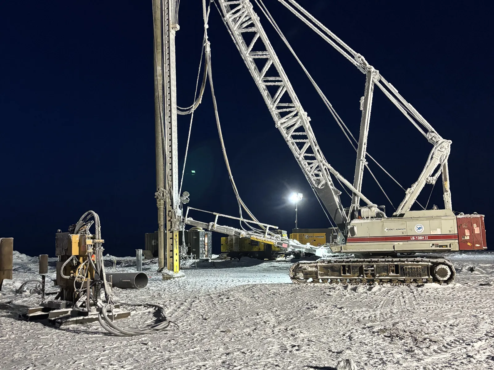 Grue de battage de pieux en opération de nuit sur un site minier nordique enneigé